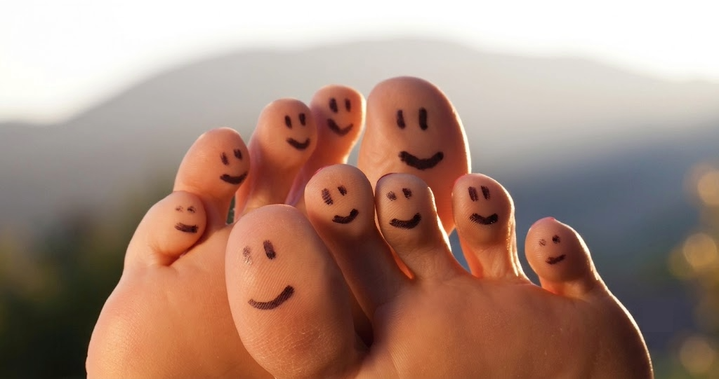 Two bare feet with happy smiley faces drawn on the toes, illustrating optimal foot health in Southeast Asia as discussed in The Reyneker Guide.