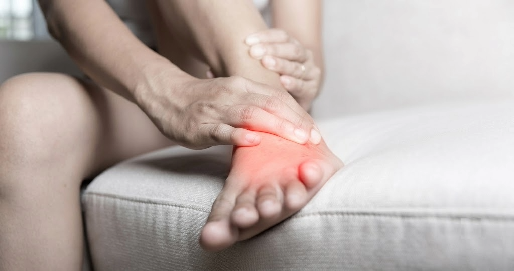 A person touching the outer side of their foot with a red highlight, demonstrating localized pain and swelling—one of the key symptoms of peroneal tendonitis.